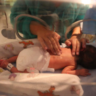 Una madre masajea a su bebé recién nacido en la uci de pediatría del Hospital de León.