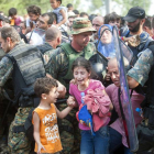 Varios refugiados ayudan ayer a uno de sus compañeros que muestra su desesperación con un niño en brazos frente a la policía de Macedonia.