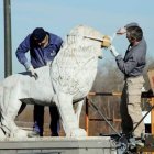 Tarbajadores del Centro de Artes y Oficios restauran uno de los leones del puente.