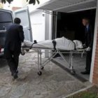 Los servicios funerarios trasladan a un vehículo el cuerpo de una de las víctimas.