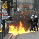 Policías antidisturbios huyen de las llamas durante una manifestación.