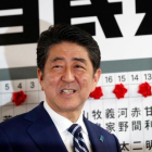 Abe sonríe mientras se dispone a colocar una rosa sobre el nombre de un candidato elegido para la Cámara baja, en la sede de su partido, en Tokio, el 22 de octubre.