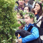 Una niña cubierta con las ramas del maio, mientras un pequeño toca la gaita.