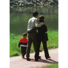 Una pareja pasea con su hijo por el paseo del río.