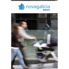 Una pareja con un carro de bebé pasa por delante de una sucursal de Novagalicia, en Vigo.