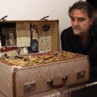 El artista Carlos España con la maleta en la que hay tierra de un cementerio leonés.