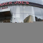 Varias personas hacen cola a la puerta de un supermercado para conseguir víveres.
