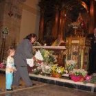 Una niña y su madre depositan un arreglo floral a los pies de la Virgen del castro