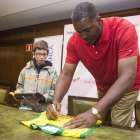 Reggie Johnson firma un autógrafo a un aficionado en la oficina central de Abanca en León.