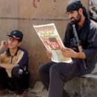 Dos hombres armados leen la prensa iraquí en el día de oración en Ciudad de Al Sáder