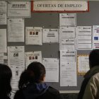 Unos parados consultan ofertas de empleo en una oficina.