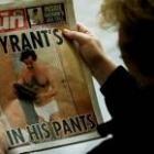 Una mujer lee el periódico en el que aparecen las fotos de Sadam en calzoncillos