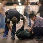 Un policía neoyorkino mira el interior de la mochila de un usuario del metro de la gran manzana