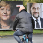 Un ciclista pasa frente a dos carteles electorales de Merkel (izquierda) y Schulz, en Essen, el 14 de septiembre.