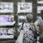 Una pareja mira pisos de alquiler en una inmobiliaria de Barcelona.