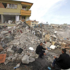 Dos hombres conversan junto a los escombros de uno de los edificios devastados.