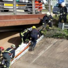 Los bomberos suben el cuerpo sin vida del joven en un puente de Córdoba.