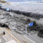 Imagen tomada el 11 de marzo que muestra una ola que desborda un dique en un pueblo.