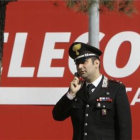 Un policía habla con su móvil frente a la sede de Telecom Italia en Rozzano