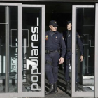 Dos policías salen de la sede central del PP, en la calle Génova de Madrid.