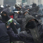 Manifiestantes antisistema lanzan botellas contra la policía italiana en Milán.