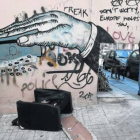Un hombre pasa ante un grafiti de denuncia en la ciudad de Atenas, este lunes.