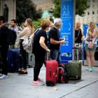 Varios turistas esperan el autobús al aeropuerto en la plaza de Catalunya.