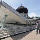 Dos vecinos pasan junto a una mezquita dañada por el terremoto, en Meuredu (Pidie Jaya).