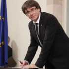 El president Carles Puigdemont en el momento de firmar la declaración, tras el pleno.