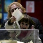 Una niña deposita el voto de su madre en la urna en Belgrado