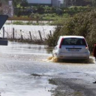 Un coche atraviesa una carretera de Huelva inundada.