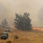 Vehículos de la Guardia Civil y de agentes forestales huyen de las llamas en Quintanilla.