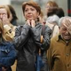 Tres personas lloran emocionadas mientras contemplan el funeral en una de las pantallas gigantes