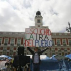 Un hombre sostiene un cartel que reza «Escuchad la ira del pueblo» en Sol.