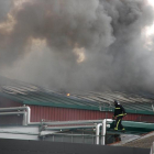 Un bombero sobre el tejado de Embutidos Rodríguez durante el operativo para sofocar el fuego. PEIO GARCÍA