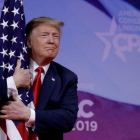 El presidente Donald Trump abrazando una bandera de su país.