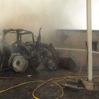 Un bombero culmina la extinción de las llamas que carbonizaron el tractor.