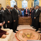 Kellyanne Conway, de rodillas y con zapatos, consulta su móvil mientras Trump y sus invitados posan para la foto oficial