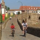 Dos ciclistas atraviesan el puente del Paso Honroso situado sobre el río Órbigo