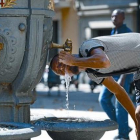 Un joven bebe agua en una fuente pública de Barcelona.