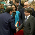 El presidente de la Generalitat, Carles Puigdemont (d), y el vicepresidente del Govern, Oriol Junqueras (i), se saludan tras aprobarse en el pleno del Parlament la declaración de independencia, con los votos de Junts pel Sí (JxSí) y la CUP.