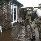 Soldados británicos cargan sacos de arena ante una casa inundada en Chertsey, a las afueras de Londres, este miércoles.