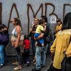 Venezolanos hacen cola frente a una pintada con la palabra hambre, en Caracas.