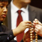 Dos niños ensartan las bolas de los números premiados de la Lotería de Navidad 2016.