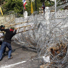 Varios activistas antigubernamentales cortan el alambre de espino colocado alrededor de la sede del Gobierno para poder acceder al complejo.