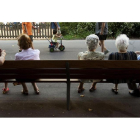 Un grupo de ancianos descansan en un banco en un parque.