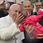 El Papa bendice a un bebé en su visita a la favela.