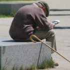 Un anciano lee el periódico sentado en uno de los parques de León.