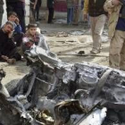 Tres adolescentes iraquíes contemplan los restos del coche bomba