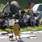 Una mujer mira a un grupo de ‘indignados’ en un campamento en Ginebra, Suiza.